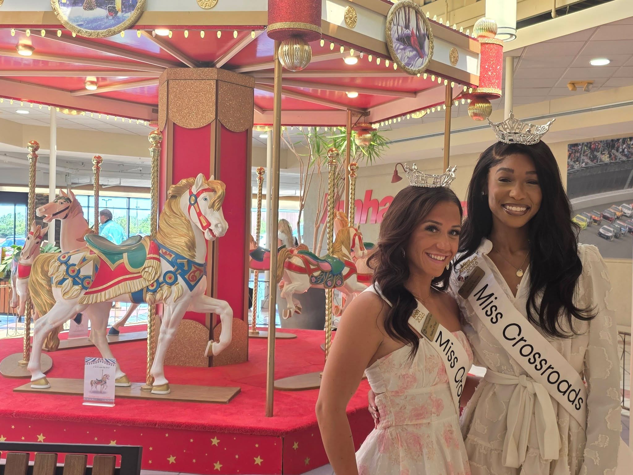 Miss Crossroads and Miss Crossroads’ Teen beside the carousel during their Jackson Crossing community visit.